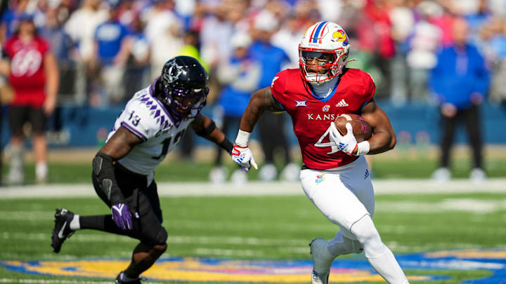 Oct 8, 2022; Lawrence, Kansas, USA; Kansas Jayhawks running back Devin Neal (4) runs with the ball past TCU Horned Frogs linebacker Dee Winters (13) during the first half at David Booth Kansas Memorial Stadium.
