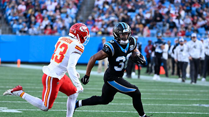 Nov 24, 2024; Charlotte, North Carolina, USA;  Carolina Panthers running back Chuba Hubbard (30) runs as Kansas City Chiefs safety Nazeeh Johnson (13) defends in the third quarter at Bank of America Stadium. Mandatory Credit: Bob Donnan-Imagn Images