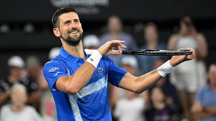 Novak Djokovic celebrates winning by pretending to play the violin on his tennis racquet during the Brisbane International.