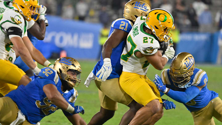 Sep 28, 2024; Pasadena, California, USA; UCLA Bruins defensive lineman Siale Taupaki (92), linebacker JonJon Vaughns (21), and defensive back Kaylin Moore (9) tackles Oregon Ducks running back Jayden Limar (27) during the fourth quarter at Rose Bowl. Mandatory Credit: Robert Hanashiro-Imagn Images