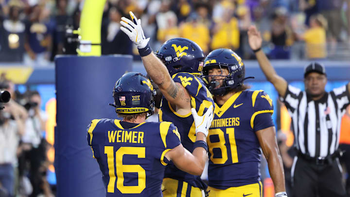 West Virginia University tight end Grayson Barnes celebrates the game-tying touchdown in the fourth quarter with teammates Jacob Barrick (81) and Jeff Weimer (16) West Virginia University tight end Grayson Barnes celebrates the game-tying touchdown in the fourth quarter with teammates Jacob Barrick (81) and Jeff Weimer (16)