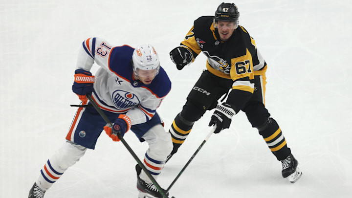 Dec 16, 2025; Pittsburgh, Pennsylvania, USA;  Edmonton Oilers center Mattias Janmark (13) moves the puck against Pittsburgh Penguins right wing Rickard Rakell (67) during the third period at PPG Paints Arena. Mandatory Credit: Charles LeClaire-Imagn Images