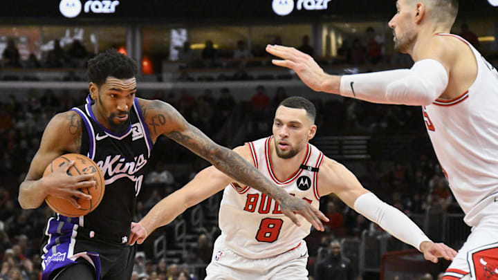 Jan 12, 2025; Chicago, Illinois, USA;  Sacramento Kings guard Malik Monk (0) drives to the basket against Chicago Bulls guard Zach LaVine (8) and  center Nikola Vucevic (9) during the second half at United Center. Mandatory Credit: Matt Marton-Imagn Images