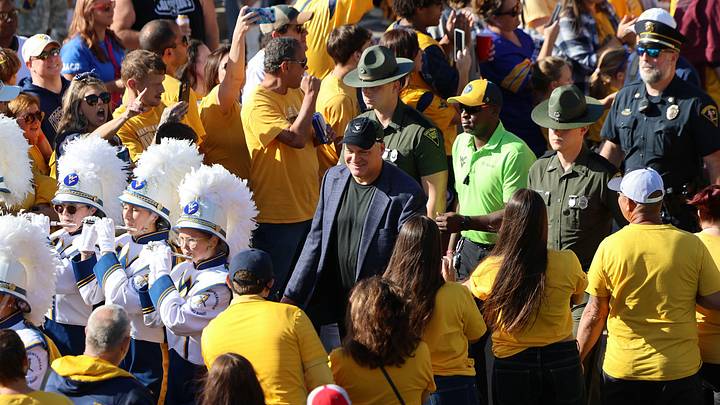 West Virginia University head coach Rich Rodriguez walks through a sea of gold Mountaineers fans ahead of the Big 12 Conference home opener against Oklahoma State