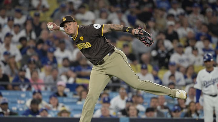 Oct 6, 2024; Los Angeles, California, USA; San Diego Padres third baseman Manny Machado (13) attempts to throw to first against Los Angeles Dodgers outfielder Tommy Edman (25) in the eighth inning during game two of the NLDS for the 2024 MLB Playoffs at Dodger Stadium. Mandatory Credit: Jayne Kamin-Oncea-Imagn Images