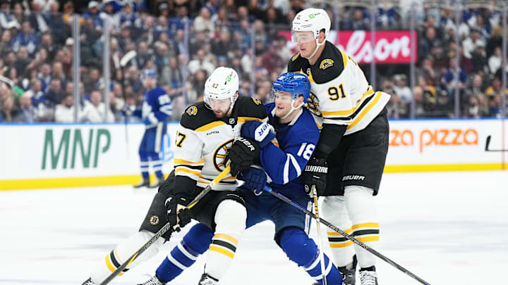 Nov 5, 2024; Toronto, Ontario, CAN; Toronto Maple Leafs center Steven Lorentz (18) battles for the puck with Boston Bruins center Mark Kastelic (47) and defenseman Nikita Zadorov (91) during the third period at Scotiabank Arena. Mandatory Credit: Nick Turchiaro-Imagn Imagess