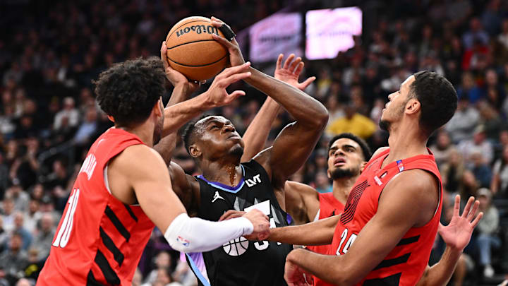 Apr 9, 2025; Salt Lake City, Utah, USA;  Utah Jazz forward Oscar Tshiebwe (34) battles to shoot the ball while being defended by Portland Trail Blazers forward Justin Minaya (10) and forward Kris Murray (24) in the first half at Delta Center. Mandatory Credit: Jamie Sabau-Imagn Images