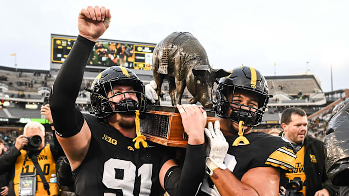 Oct 25, 2025; Iowa City, Iowa, USA; Iowa Hawkeyes defensive lineman Jonah Pace (91) and defensive lineman Bryce Hawthorne (96) carry off the Floyd of Rosedale trophy after their victory over the Minnesota Golden Gophers at Kinnick Stadium. Mandatory Credit: Jeffrey Becker-Imagn Images