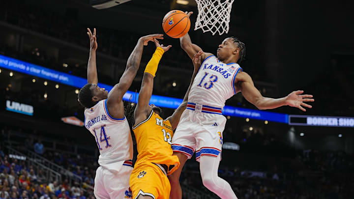 Dec 7, 2025; Kansas City, Missouri, USA; Missouri Tigers guard Sebastian Mack (12) shoots against Kansas Jayhawks guard Melvin Council Jr. (14) and guard Elmarko Jackson (13) during the second half at T-Mobile Center. Mandatory Credit: Jay Biggerstaff-Imagn Images