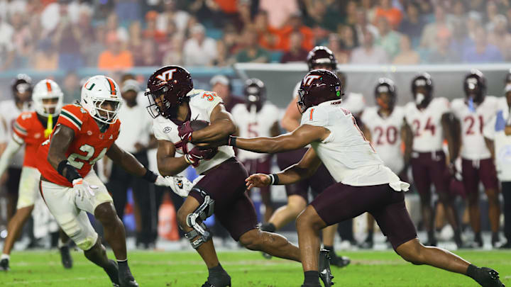 Sep 27, 2024; Miami Gardens, Florida, USA; Virginia Tech Hokies running back Bhayshul Tuten (33) takes a handoff from quarterback Kyron Drones (1) against the Miami Hurricanes during the fourth quarter at Hard Rock Stadium. Mandatory Credit: Sam Navarro-Imagn Images Sep 27, 2024; Miami Gardens, Florida, USA; Virginia Tech Hokies running back Bhayshul Tuten (33) takes a handoff from quarterback Kyron Drones (1) against the Miami Hurricanes during the fourth quarter at Hard Rock Stadium. Mandatory Credit: Sam Navarro-Imagn Images