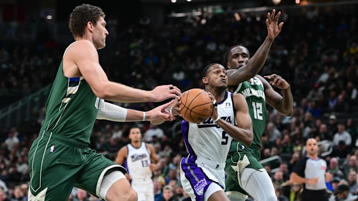 Jan 14, 2025; Milwaukee, Wisconsin, USA;  Sacramento Kings guard De'Aaron Fox (5) drives for the basket between Milwaukee Bucks center Brook Lopez (11) and guard Taurean Prince (12) in the second quarter at Fiserv Forum. Mandatory Credit: Benny Sieu-Imagn Images