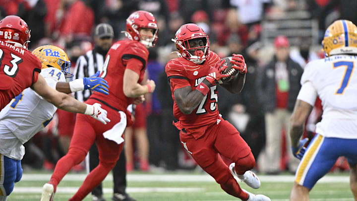 Nov 23, 2024; Louisville, Kentucky, USA;  Louisville Cardinals running back Isaac Brown (25) runs against Pittsburgh Panthers defensive lineman Jimmy Scott (44) during the first quarter at L&N Federal Credit Union Stadium. Mandatory Credit: Jamie Rhodes-Imagn Images