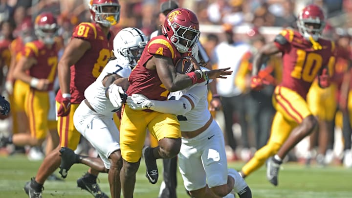 Oct 12, 2024; Los Angeles, California, USA; USC Trojans running back Woody Marks (4) runs the ball for a first down before he is stopped by Penn State Nittany Lions safety Jaylen Reed (1) and cornerback Zion Tracy (7) in the first half at United Airlines Field at the Los Angeles Memorial Coliseum. Mandatory Credit: Jayne Kamin-Oncea-Imagn Images Oct 12, 2024; Los Angeles, California, USA; USC Trojans running back Woody Marks (4) runs the ball for a first down before he is stopped by Penn State Nittany Lions safety Jaylen Reed (1) and cornerback Zion Tracy (7) in the first half at United Airlines Field at the Los Angeles Memorial Coliseum. Mandatory Credit: Jayne Kamin-Oncea-Imagn Images