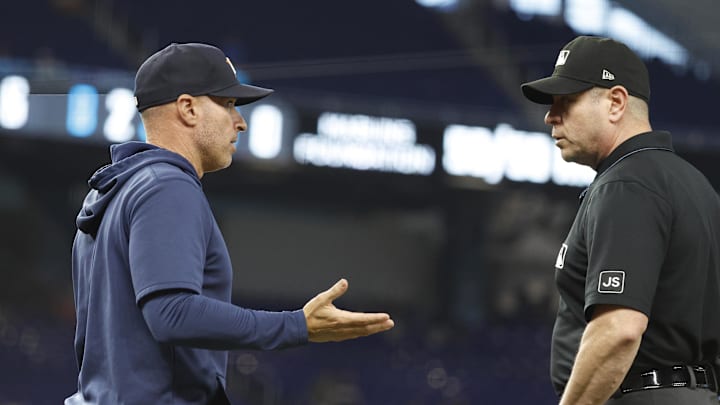 A man in a navy blue hoodie and black hat talking to a man in a black T-shirt and black hat