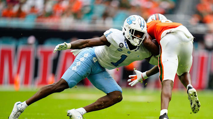 Oct 8, 2022; Miami Gardens, Florida, USA; North Carolina Tar Heels defensive back Tony Grimes (1) tackles Miami Hurricanes wide receiver Frank Ladson Jr. (8) during the first half at Hard Rock Stadium. Mandatory Credit: Rich Storry-Imagn Images