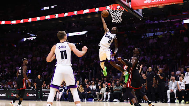 Nov 4, 2024; Miami, Florida, USA; Sacramento Kings guard Malik Monk (0) dunks the basketball again st Miami Heat center Bam Adebayo (13) during the fourth quarter at Kaseya Center. Mandatory Credit: Sam Navarro-Imagn Images
