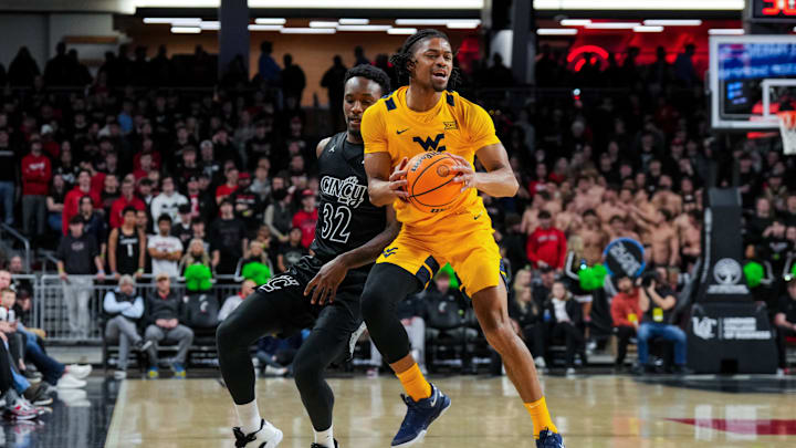 Feb 5, 2026; Cincinnati, Ohio, USA;  West Virginia Mountaineers guard Jasper Floyd (1) battles for the loose ball against Cincinnati Bearcats forward Jalen Celestine (32) in the first half at Fifth Third Arena. Mandatory Credit: Aaron Doster-Imagn Images