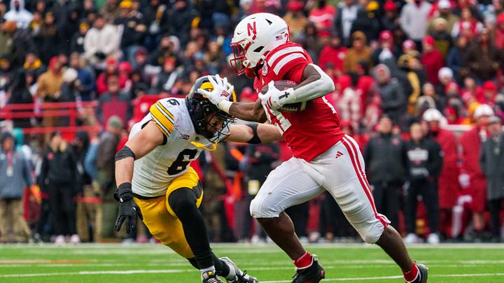 Nov 28, 2025; Lincoln, Nebraska, USA; Nebraska Cornhuskers running back Emmett Johnson (21) runs against Iowa Hawkeyes defensive back Zach Lutmer (6) during the third quarter at Memorial Stadium. Mandatory Credit: Dylan Widger-Imagn Images