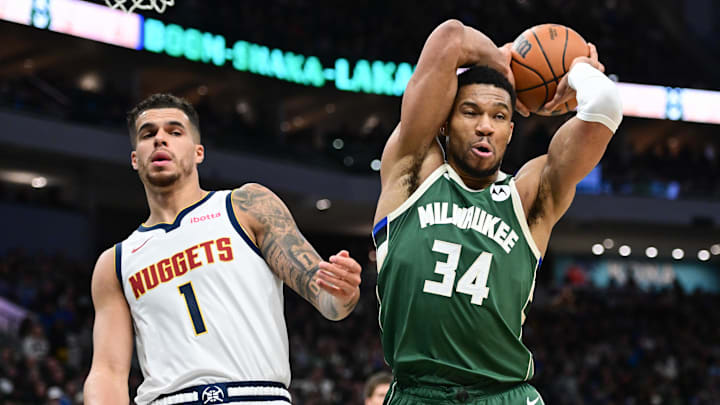 Feb 27, 2025; Milwaukee, Wisconsin, USA; Milwaukee Bucks forward Giannis Antetokounmpo (34) grabs a rebound against Denver Nuggets forward Michael Porter Jr. (1) in the third quarter at Fiserv Forum. Mandatory Credit: Benny Sieu-Imagn Images