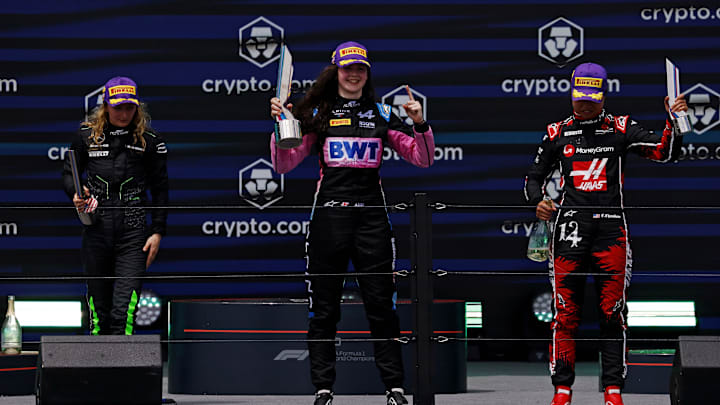 May 4, 2024; Miami Gardens, Florida, USA; F1 Academy driver Doriane Pin (28), F1 Academy driver Abbi Pulling (9) and F1 Academy driver Chloe Chambers (14) celebrate on the podium after the F1 Academy First Race at Miami International Autodrome. Pulling won first place, Pin won second place and Chambers won third place. Mandatory Credit: Peter Casey-Imagn Images