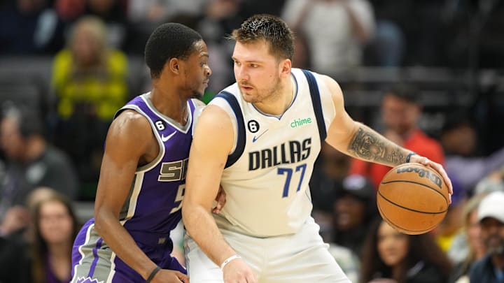 Feb 11, 2023; Sacramento, California, USA; Dallas Mavericks guard Luka Doncic (77) dribbles against Sacramento Kings guard De'Aaron Fox (5) during the fourth quarter at Golden 1 Center. Mandatory Credit: Darren Yamashita-Imagn Images