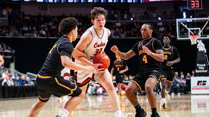 Cedar Fall's Will Gerdes (32) drives to the basket past Johnston's Emri Jones (4) and Nicare Cavil (1) on March 13, 2026, at Casey’s Center in Des Moines.