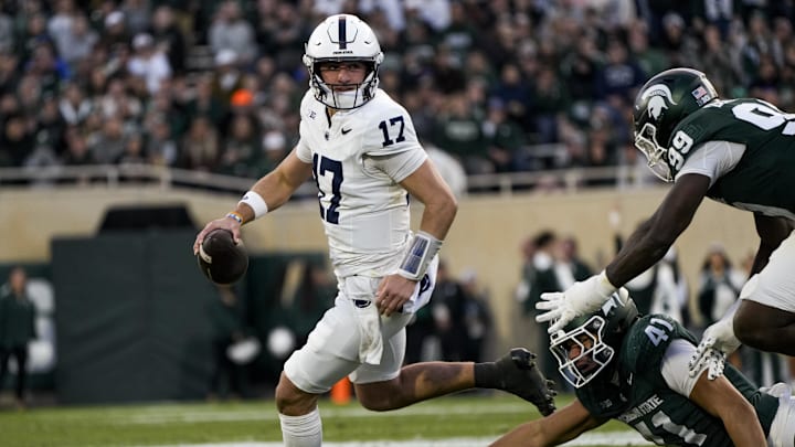 Nov 15, 2025; East Lansing, Michigan, USA; Penn State Nittany Lions quarterback Ethan Grunkemeyer (17) runs out of the pocket  as Michigan State Spartans linebacker David Santiago (41) and defensive lineman Quindarius Dunnigan (99) leap for the tackle in the second quarter at Spartan Stadium. Mandatory Credit: Brendan Mullin-Imagn Images