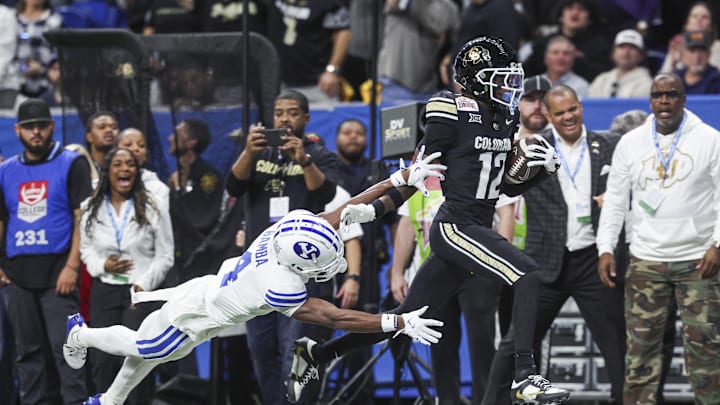 Dec 28, 2024; San Antonio, TX, USA; Colorado Buffaloes wide receiver Travis Hunter (12) runs with the ball as Brigham Young Cougars cornerback Mory Bamba (4) attempts to make a tackle during the second quarter at Alamodome. Mandatory Credit: Troy Taormina-Imagn Images