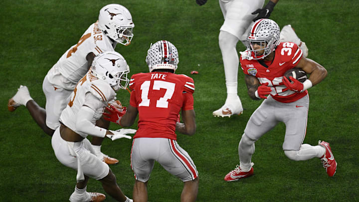 Jan 10, 2025; Arlington, Texas, USA; Ohio State Buckeyes running back TreVeyon Henderson (32) runs against Texas Longhorns defensive back Andrew Mukuba (4) and defensive back Malik Muhammad (5) as Buckeyes wide receiver Carnell Tate (17) blocks during the second quarter of the College Football Playoff semifinal in the Cotton Bowl at AT&T Stadium. Mandatory Credit: Jerome Miron-Imagn Images