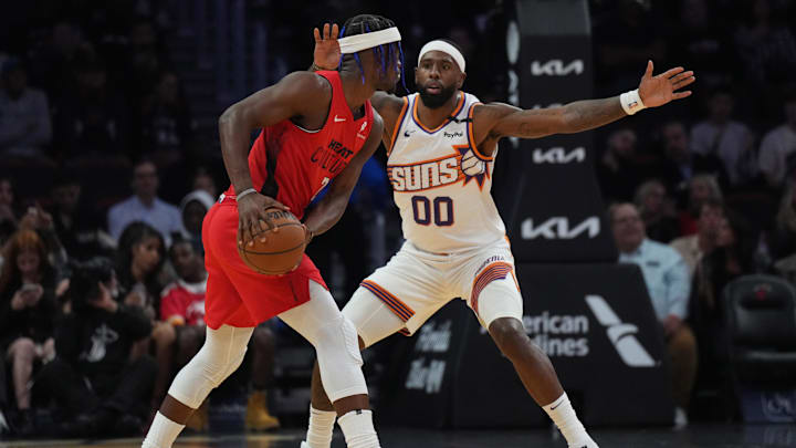 Dec 7, 2024; Miami, Florida, USA;  Miami Heat forward Jimmy Butler (22) controls the ball against Phoenix Suns forward Royce O'Neale (00) during the first half at Kaseya Center. Mandatory Credit: Jim Rassol-Imagn Images