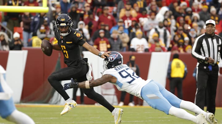 Dec 1, 2024; Landover, Maryland, USA; Washington Commanders quarterback Jayden Daniels (5) runs with the ball as Tennessee Titans linebacker Jaylen Harrell (92) tackles during the second half at Northwest Stadium. Mandatory Credit: Amber Searls-Imagn Images