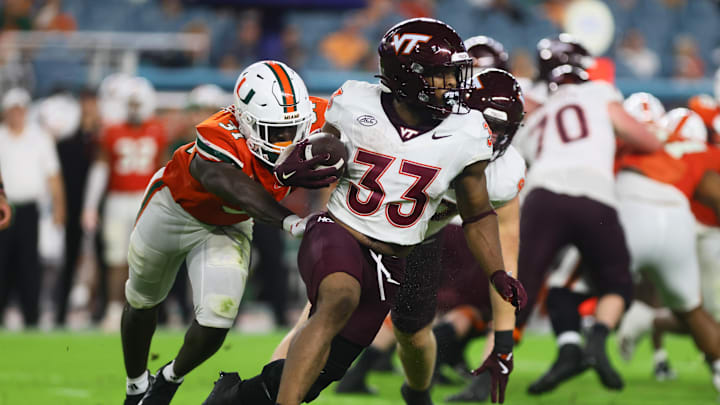 Sep 27, 2024; Miami Gardens, Florida, USA; Virginia Tech Hokies running back Bhayshul Tuten (33) runs with the football past Miami Hurricanes linebacker Wesley Bissainthe (31) during the second quarter at Hard Rock Stadium. Mandatory Credit: Sam Navarro-Imagn Images