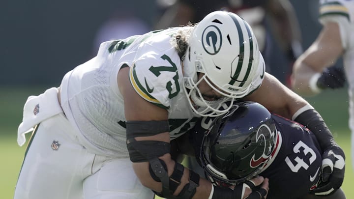 Oct 20, 2024; Green Bay, Wisconsin, USA; Green Bay Packers guard Sean Rhyan (75) tackles Houston Texans linebacker Neville Hewitt (43) after an interception during the first quarter of their game at Lambeau Field. Mandatory Credit: Mark Hoffman/Milwaukee Journal Sentinel via the USA TODAY NETWORK-Wisconsin-Imagn Images