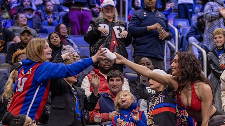 Dec 2, 2023; Detroit, Michigan, USA; A Pistons Dancer gives a fan a tee shirt during the second half