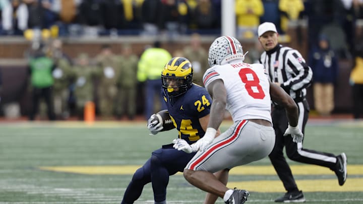 Nov 29, 2025; Ann Arbor, Michigan, USA; Michigan Wolverines running back Bryson Kuzdzal (24) runs the ball defended by Ohio State Buckeyes linebacker Arvell Reese (8) in the first half at Michigan Stadium. Mandatory Credit: Rick Osentoski-Imagn Images