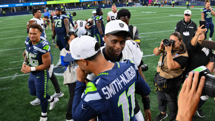 Raiders quarterback Geno Smith (7) and Seahawks receiver Jaxon Smith-Njigba (11) hug during the preseason.