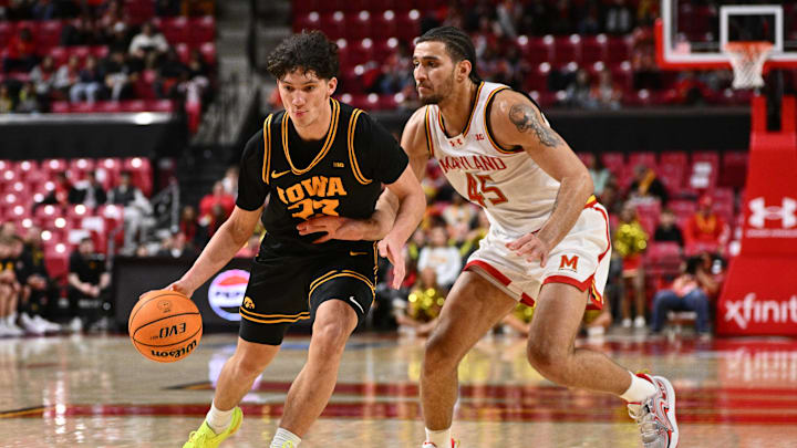 Feb 11, 2026; College Park, Maryland, USA;  Iowa Hawkeyes guard Isaia Howard (#23) controls the ball while being defended by Maryland Terrapins center Colin Metcalf (45) in the first half at Xfinity Center. Mandatory Credit: Jamie Sabau-Imagn Images