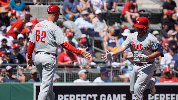 Mar 11, 2025; Fort Myers, Florida, USA; Philadelphia Phillies Buddy Kennedy (19) crosses home plate and gets a high five from coach Dusty Wathan (62) after he hit a fly ball homer to left field during the second inning of their game against the Boston Red Sox at JetBlue Park at Fenway South. 