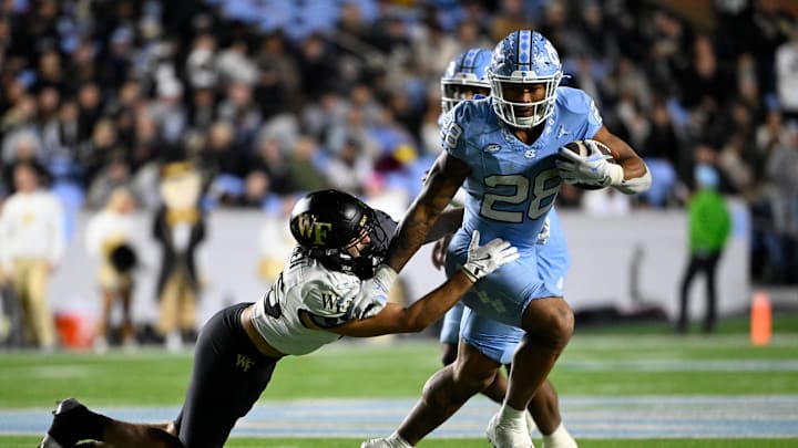 Nov 16, 2024; Chapel Hill, North Carolina, USA; North Carolina Tar Heels running back Omarion Hampton (28) runs as Wake Forest Demon Deacons defensive back Nick Andersen (45) defends in the third quarter at Kenan Memorial Stadium. Mandatory Credit: Bob Donnan-Imagn Images Nov 16, 2024; Chapel Hill, North Carolina, USA; North Carolina Tar Heels running back Omarion Hampton (28) runs as Wake Forest Demon Deacons defensive back Nick Andersen (45) defends in the third quarter at Kenan Memorial Stadium. Mandatory Credit: Bob Donnan-Imagn Images