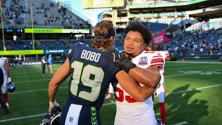 Oct 6, 2024; Seattle, Washington, USA; Seattle Seahawks wide receiver Jake Bobo (19) and New York Giants linebacker Darius Muasau (53) hug after the game at Lumen Field. Mandatory Credit: Steven Bisig-Imagn Images