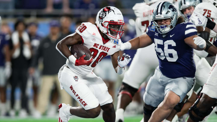 Dec 28, 2023; Orlando, FL, USA; NC State running back Kendrick Raphael (20) runs the ball against Kansas State defensive tackle Damian Ilalio (56) in the first quarter at Camping World Stadium. Mandatory Credit: Jeremy Reper-USA TODAY Sports Dec 28, 2023; Orlando, FL, USA; NC State running back Kendrick Raphael (20) runs the ball against Kansas State defensive tackle Damian Ilalio (56) in the first quarter at Camping World Stadium. Mandatory Credit: Jeremy Reper-USA TODAY Sports