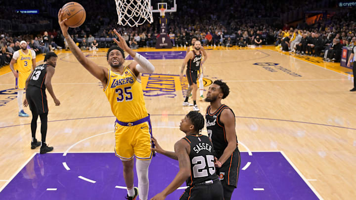 Feb 13, 2024; Los Angeles, California, USA;  Los Angeles Lakers forward Christian Wood (35) drives past Detroit Pistons guard Marcus Sasser (25) and guard Troy Brown, Jr. in the first half at Crypto.com Arena. Mandatory Credit: Jayne Kamin-Oncea-Imagn Images