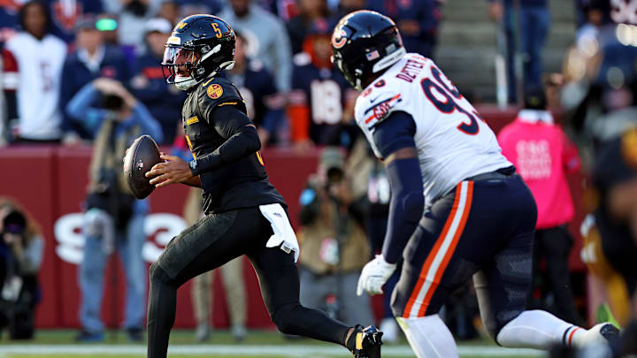 Oct 27, 2024; Landover, Maryland, USA; Washington Commanders quarterback Jayden Daniels (5) runs with the ball against Chicago Bears defensive tackle Gervon Dexter Sr. (99) during the first quarter at Commanders Field. Mandatory Credit: Peter Casey-Imagn Images