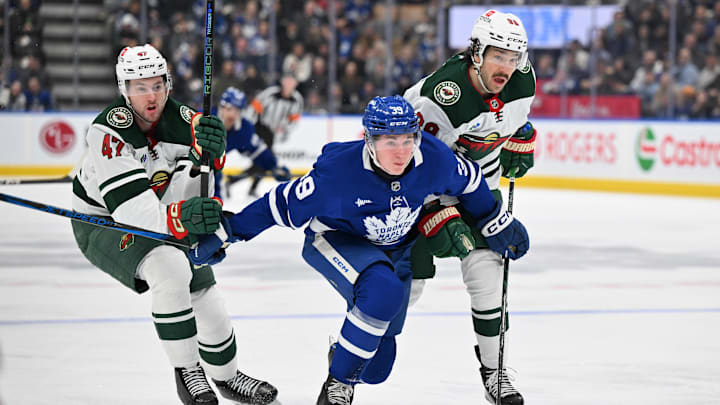 Jan 29, 2025; Toronto, Ontario, CAN;  Toronto Maple Leafs forward Fraser Minten (39) tries to skate past Minnesota Wild defensemen Jake Middleton (5) and Declan Chisholm (47) in the first period at Scotiabank Arena. Mandatory Credit: Dan Hamilton-Imagn Images
