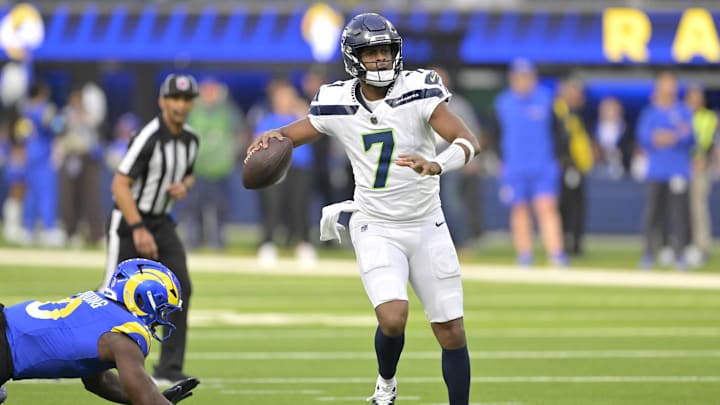 Jan 5, 2025; Inglewood, California, USA; Seattle Seahawks quarterback Geno Smith (7) scrambles away from Los Angeles Rams linebacker Byron Young (0) and throws for a touchdown in the first half at SoFi Stadium. Mandatory Credit: Jayne Kamin-Oncea-Imagn Images