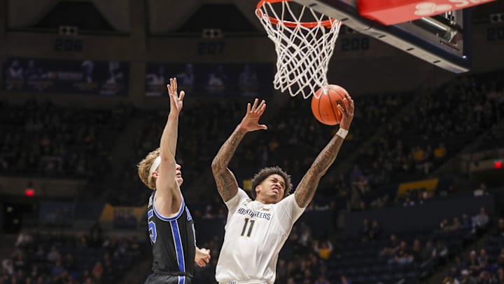 Feb 11, 2025; Morgantown, West Virginia, USA; West Virginia Mountaineers guard Jonathan Powell (11) shoots against Brigham Young Cougars forward Richie Saunders (15) during the first half at WVU Coliseum. Mandatory Credit: Ben Queen-Imagn Images