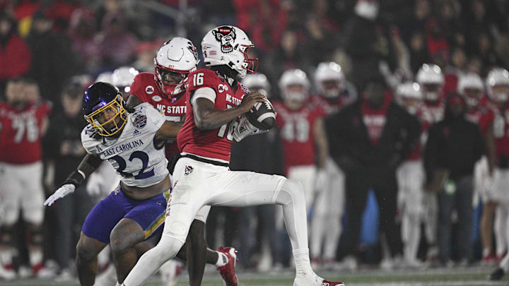 Dec 28, 2024; Annapolis, MD, USA;  North Carolina State Wolfpack quarterback CJ Bailey (16)] scrambles away from East Carolina Pirates linebacker Ryheem Craig (32) during the first half of the Go Bowling Military Bowl at Navy-Marine Corps Memorial Stadium. Mandatory Credit: Tommy Gilligan-Imagn Images