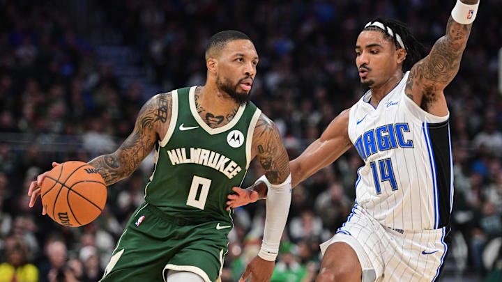 Dec 21, 2023; Milwaukee, Wisconsin, USA;  Milwaukee Bucks guard Damian Lillard (0) drives for the basket against Orlando Magic guard Gary Harris (14) in the second quarter at Fiserv Forum. Mandatory Credit: Benny Sieu-Imagn Images