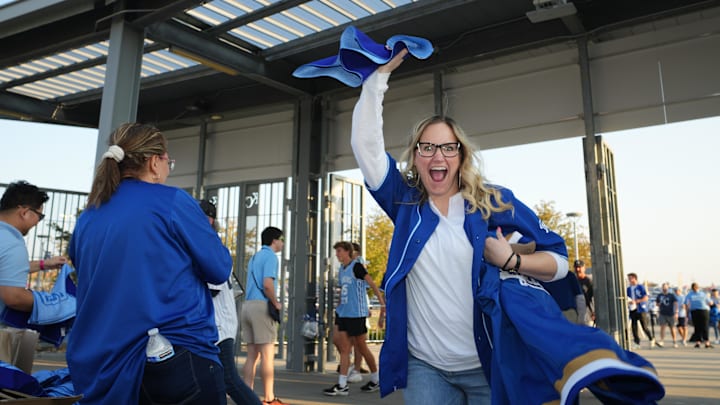 Oct 10, 2024; Kansas City, Missouri, USA; A Kansas City Royals fan cheers after receiving a rally towel while entering Kauffman Stadium for game four of the NLDS for the 2024 MLB Playoffs. Mandatory Credit: Jay Biggerstaff-Imagn Images