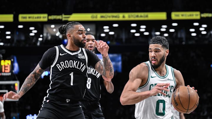 Mar 15, 2025; Brooklyn, New York, USA; Boston Celtics forward Jayson Tatum (0) drives past Brooklyn Nets guard D'Angelo Russell (1) during the second half at Barclays Center. Mandatory Credit: John Jones-Imagn Images